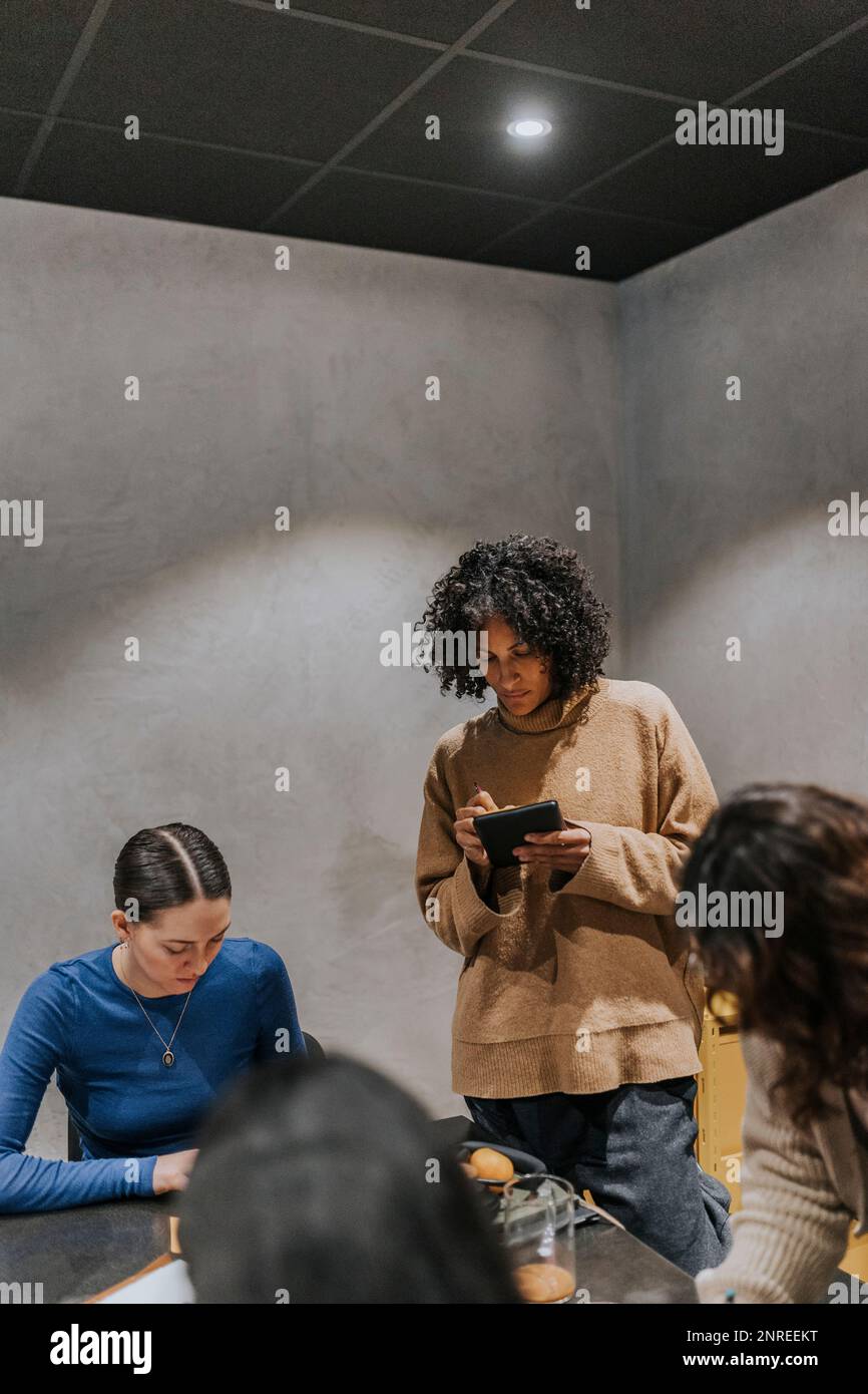 Businesswoman taking notes while discussing with female colleagues in creative office Stock Photo