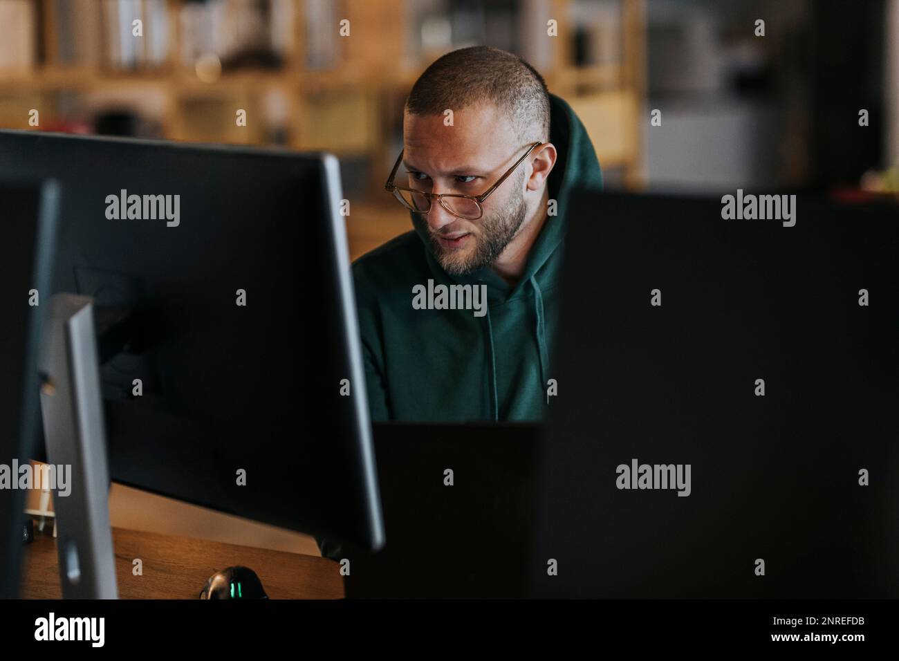 Young male programmer working on computer in startup company Stock Photo