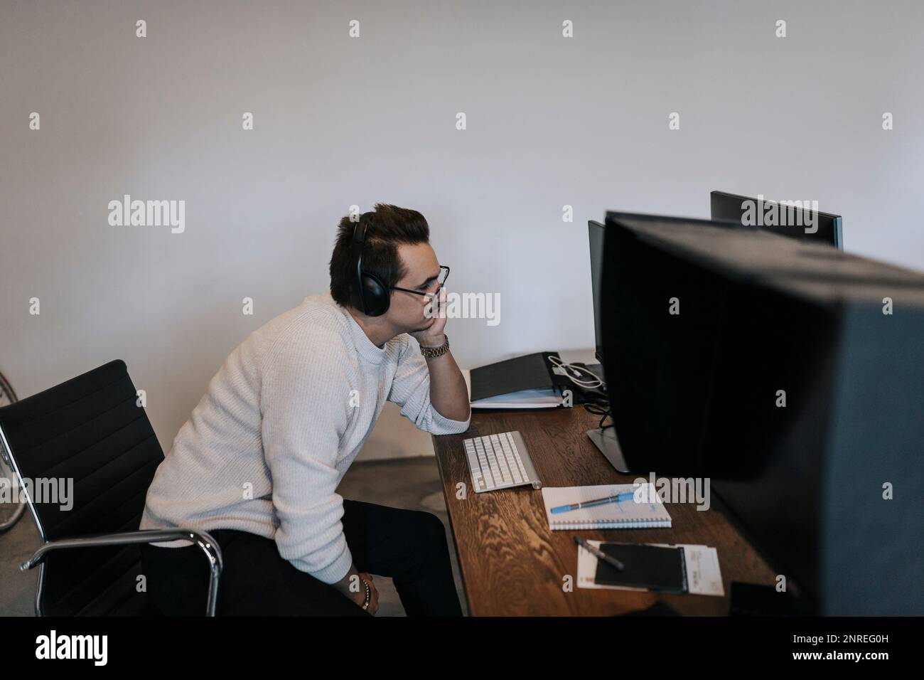 Businessman with hand on chin working over computer at desk in creative office Stock Photo