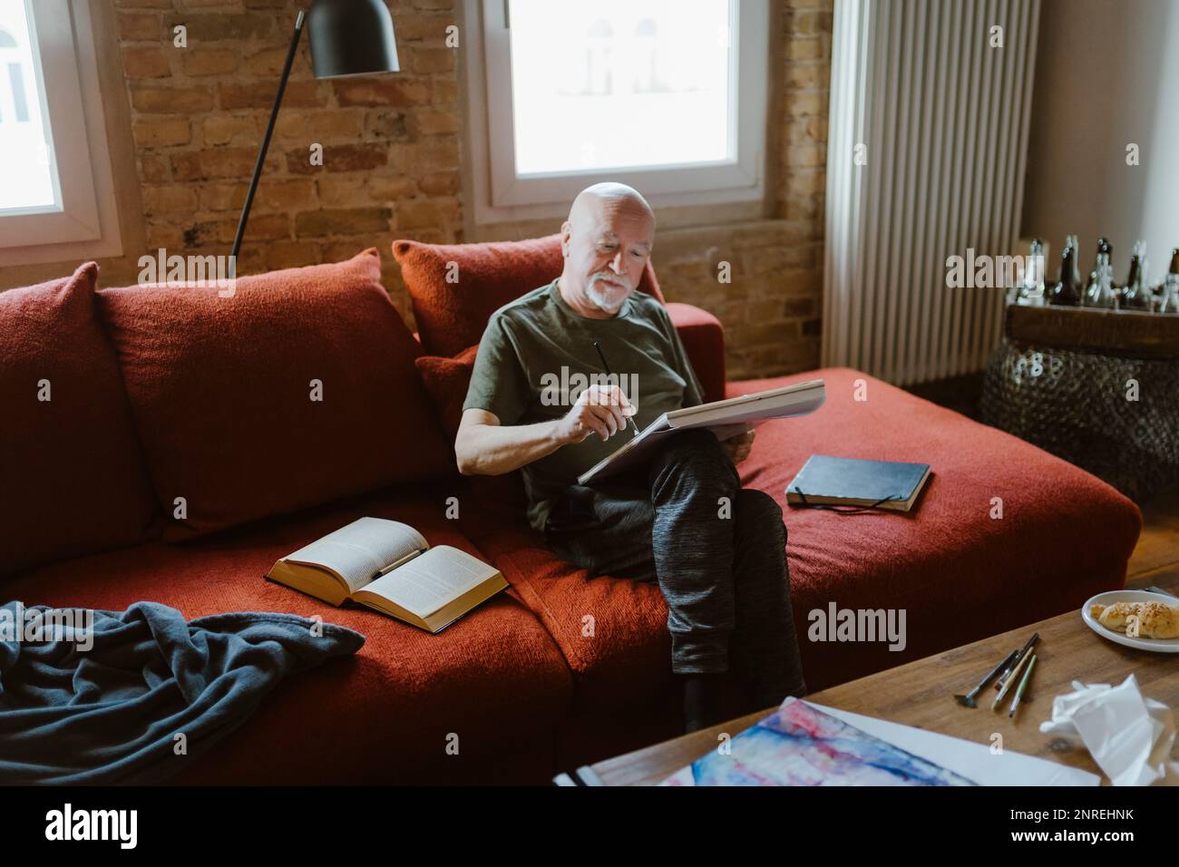 Senior man painting while sitting on sofa at home Stock Photo