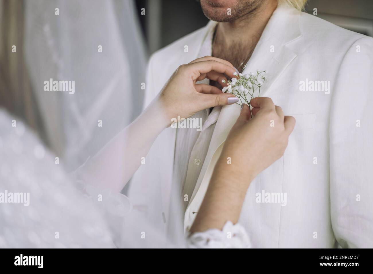 Midsection of bride adjusting boutonniere in groom's pocket on wedding Stock Photo