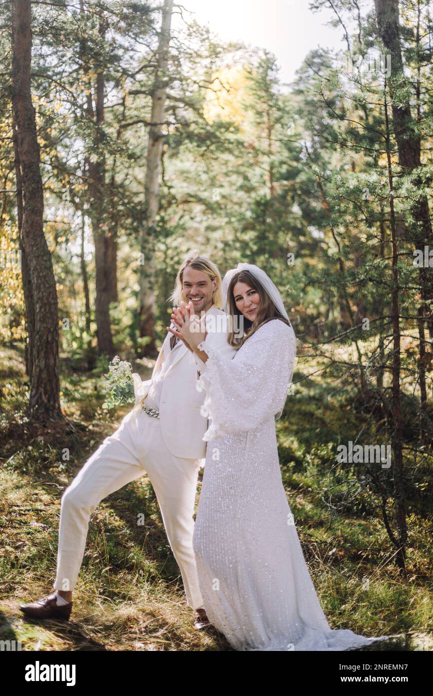 Happy bride and groom holding hands while enjoying in forest Stock Photo
