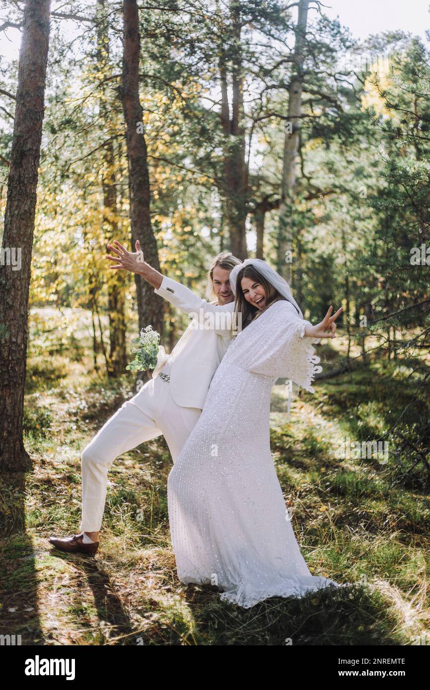 Cheerful newlywed bride and groom gesturing in forest Stock Photo