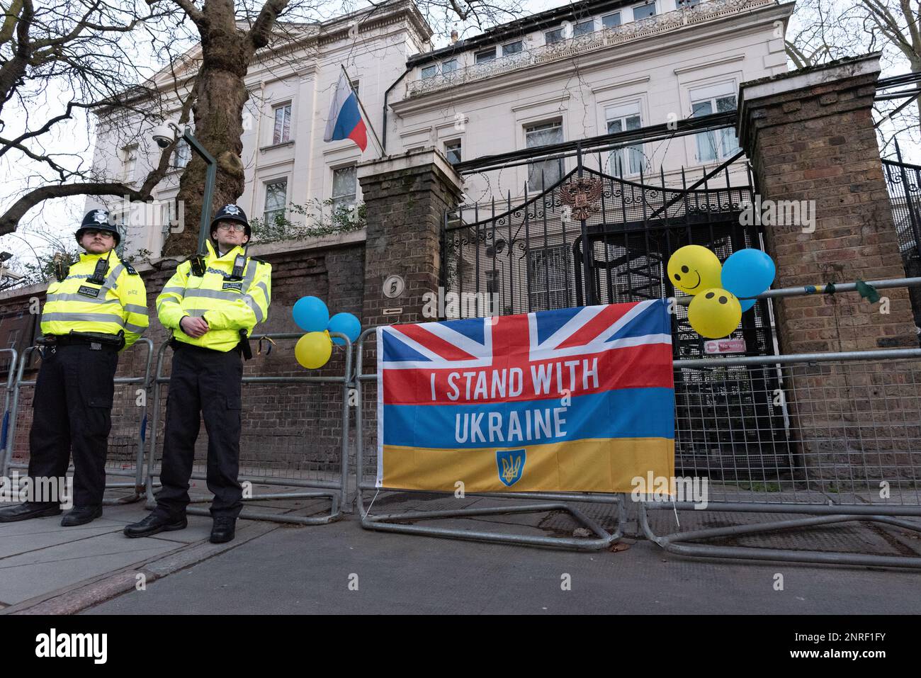 London, UK. 24 February, 2023. The entrance of the Embassy of Russian where a flag proclaiming 'I Stand With Ukraine' has been tied, with baloons, whi Stock Photo
