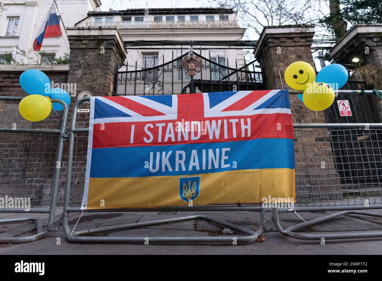 London, UK. 24 February, 2023. The entrance of the Embassy of Russian where a flag proclaiming 'I Stand With Ukraine' has been tied, along with baloon Stock Photo