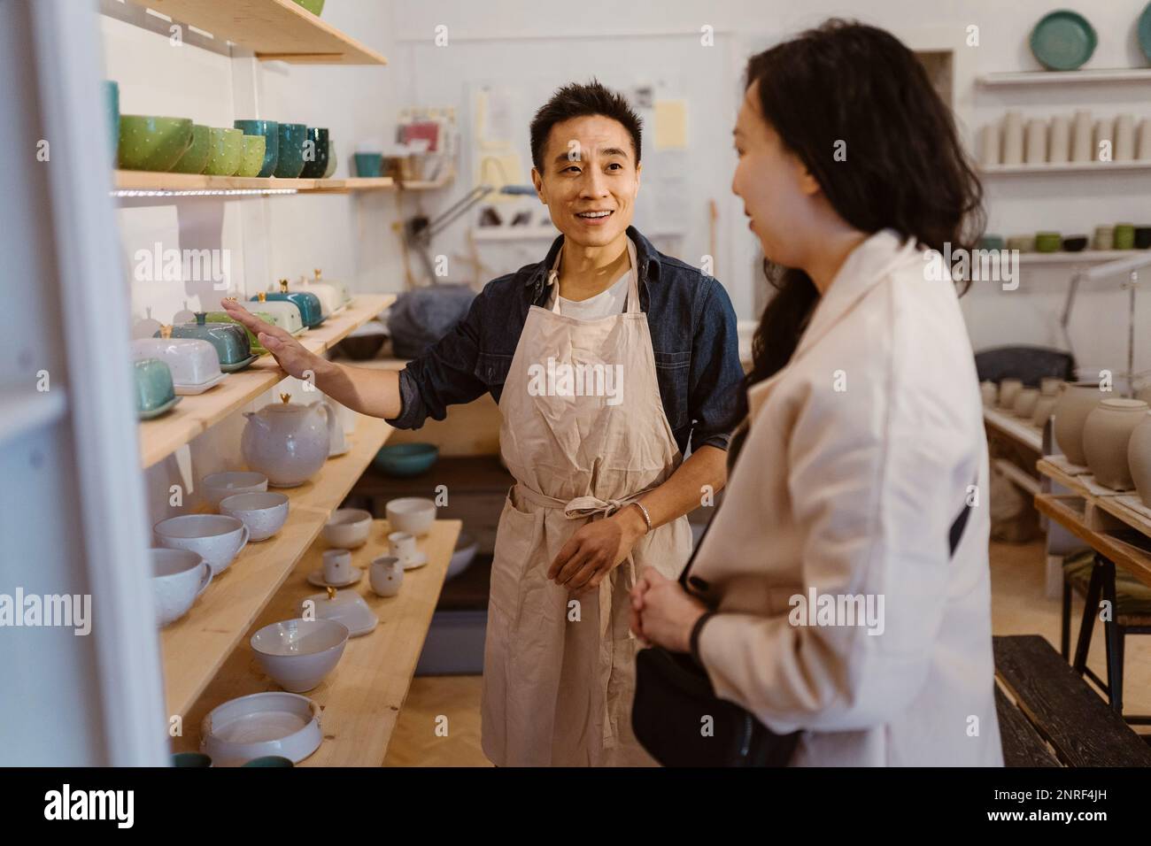 Craftsman assisting female customer while buying ceramics at
