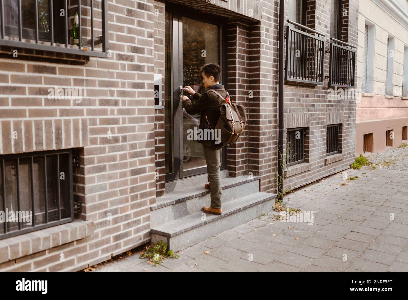 Man standing on steps while locking door of apartment Stock Photo