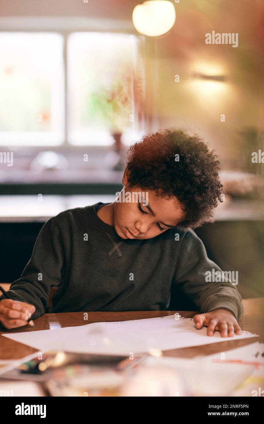 Boy with curly hair doing homework at home Stock Photo