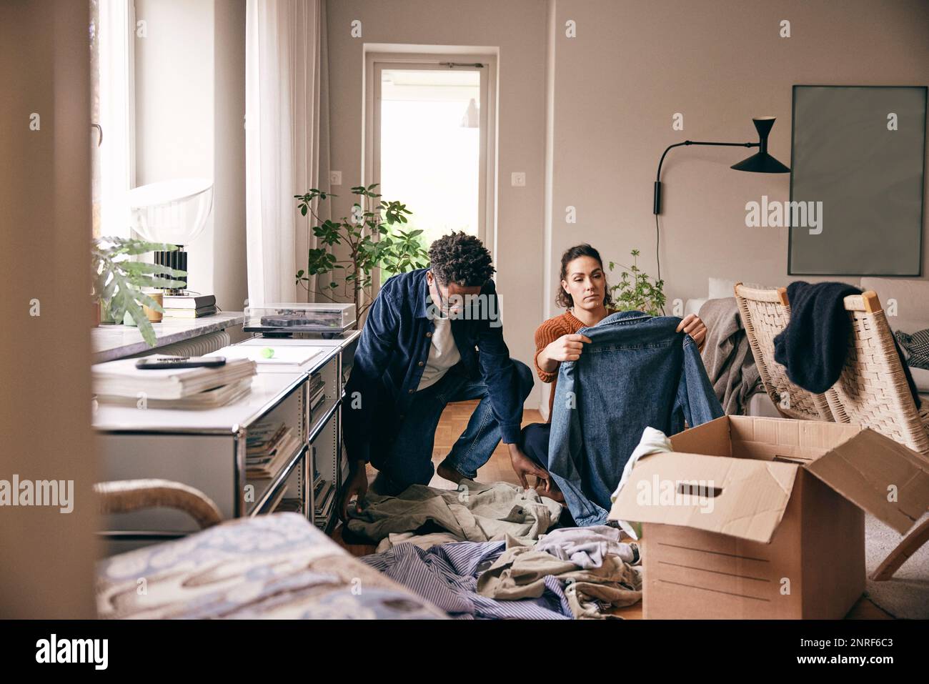 Couple helping each other while sorting out old clothes at home Stock Photo