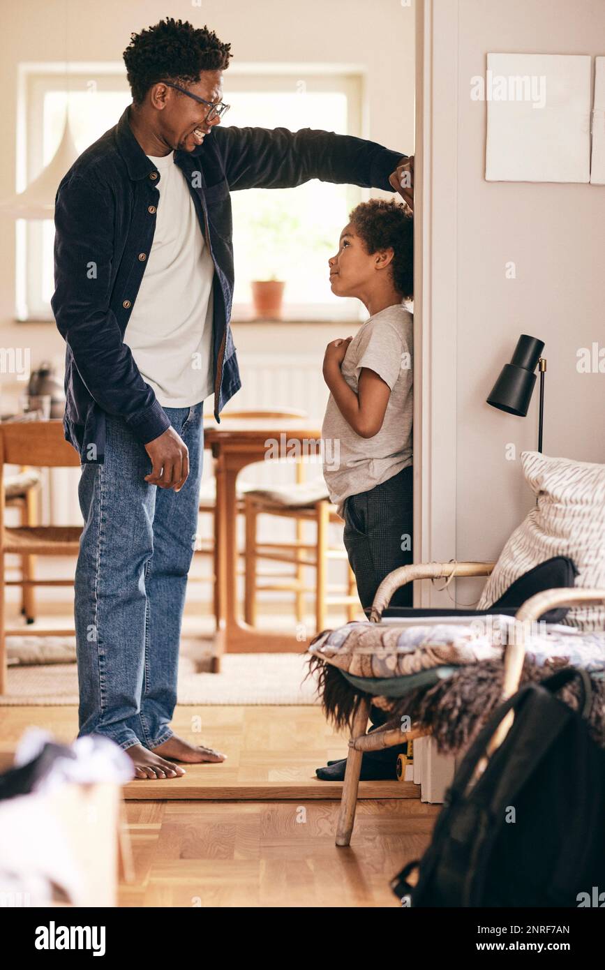 Father measuring height of son standing at doorway of home Stock Photo