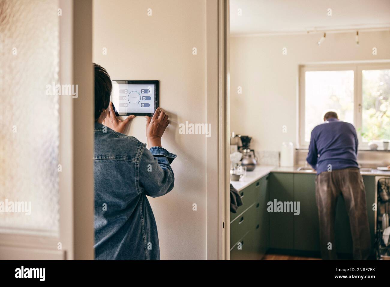 Rear view of woman using digital tablet mounted on wall at home Stock Photo