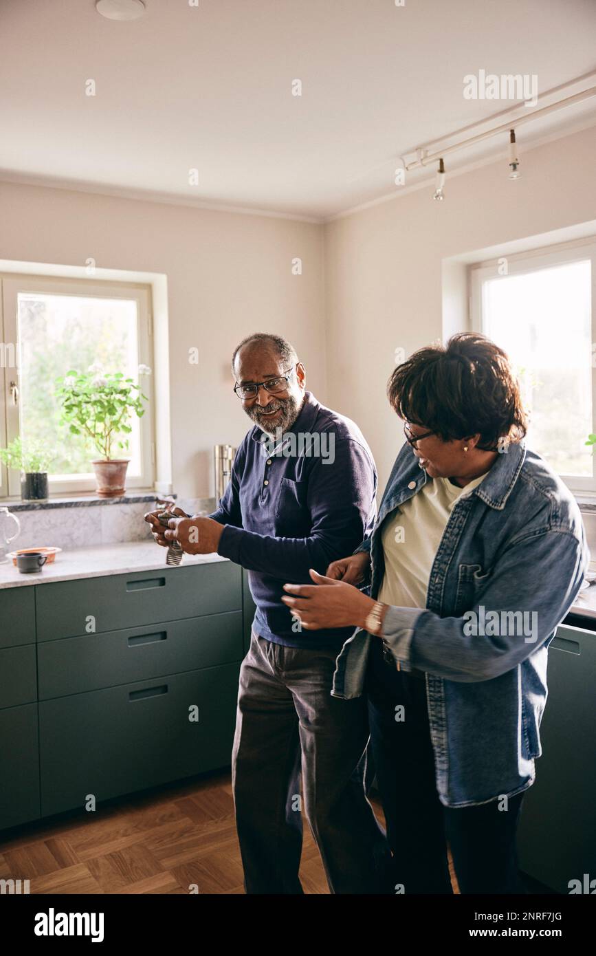 Playful senior couple dancing with each other while standing in kitchen at home Stock Photo