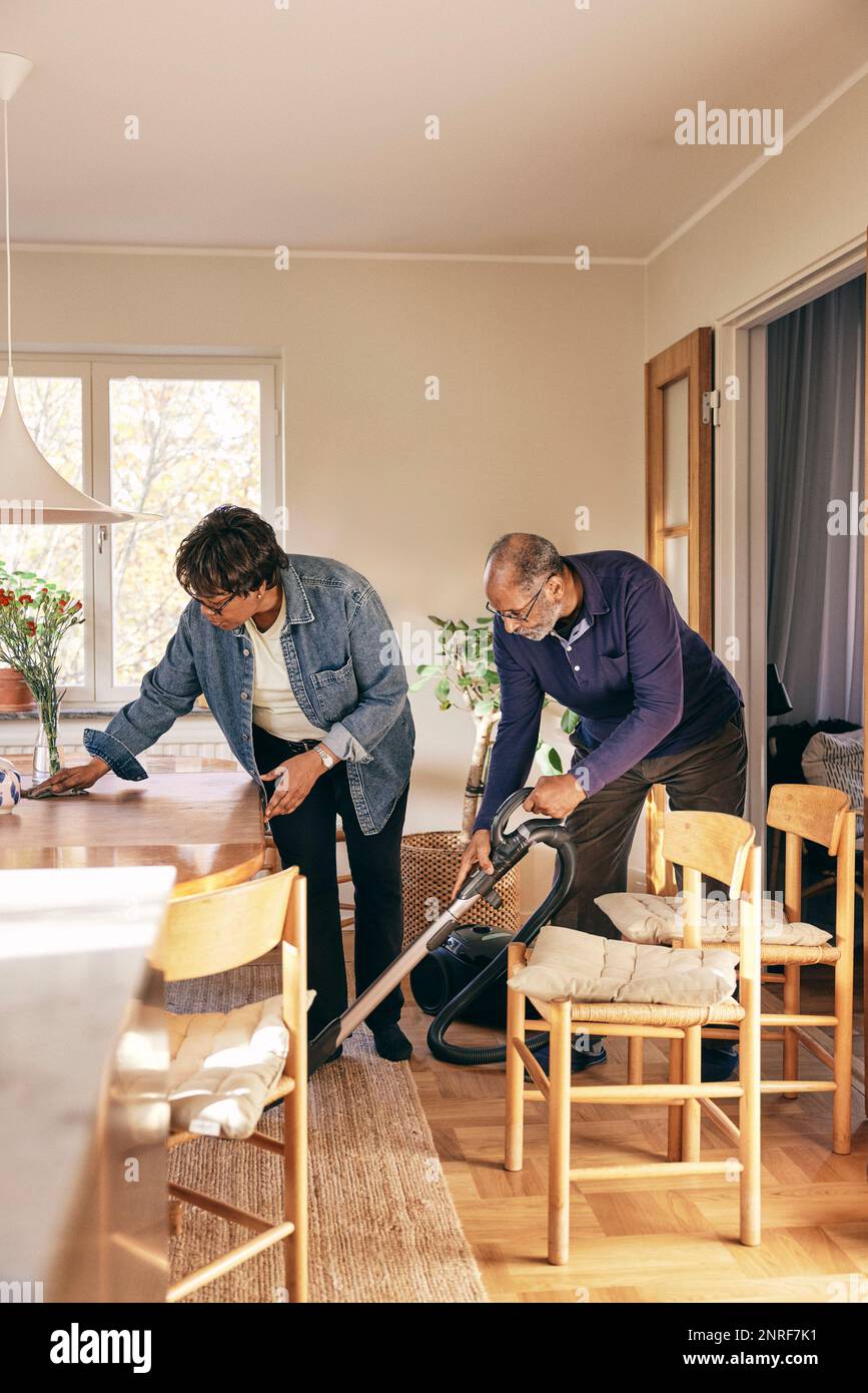 Senior couple helping each other while cleaning home Stock Photo