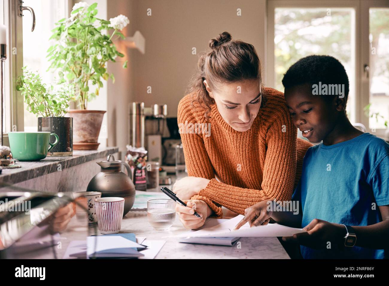Mother assisting son while doing homework at home Stock Photo
