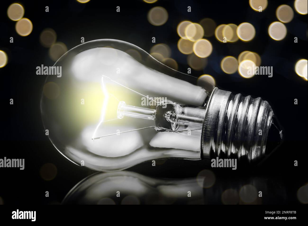 close up of tungsten light bulb with glow on dark background and defocus lights Stock Photo