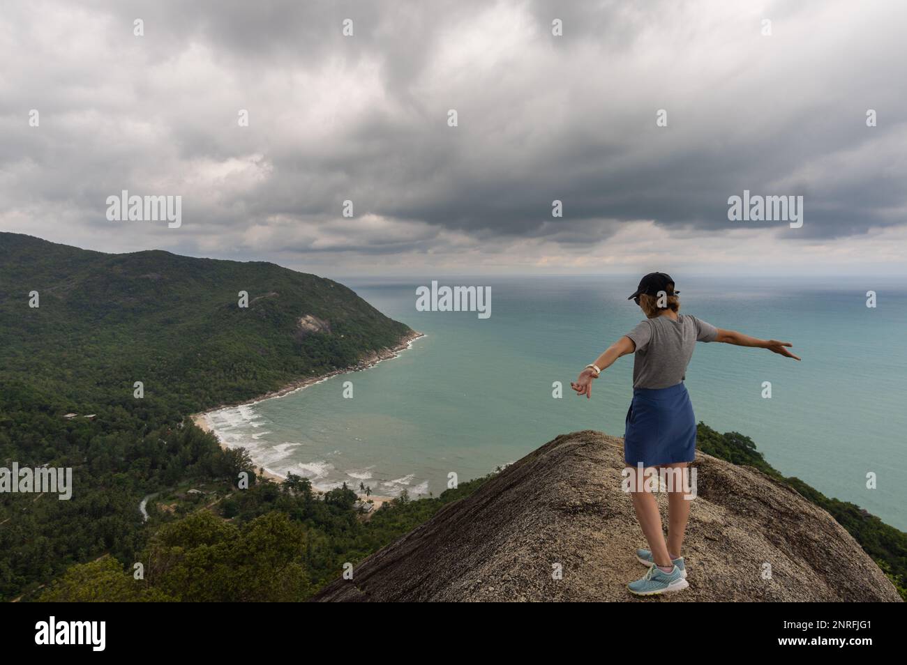 woman raising her arms on the bottle beach viewpoint. Stock Photo