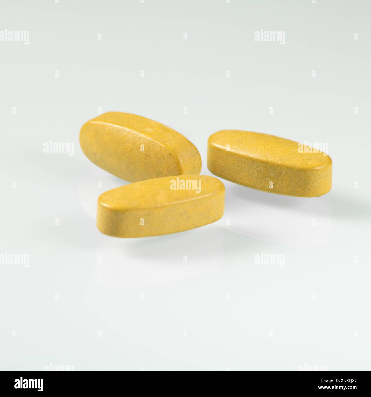 Three big yellow tablets with dietary supplements for seniors closeup