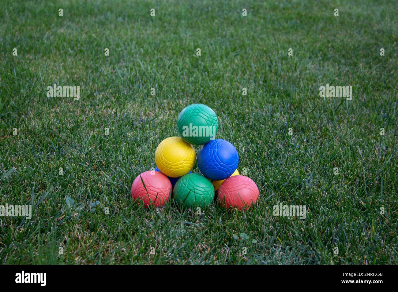 Image of a pyramid of colored bowls in a green meadow. Stock Photo