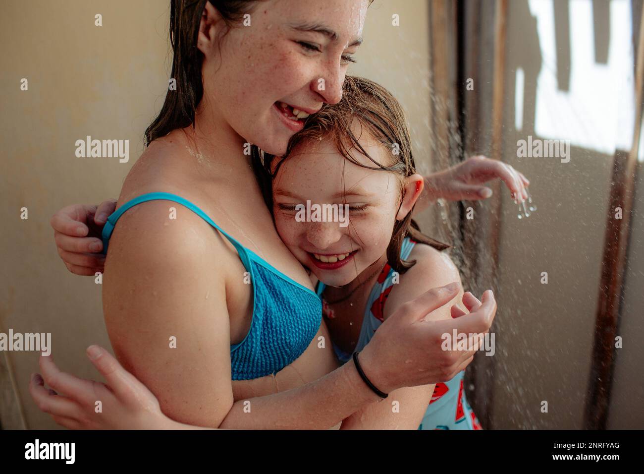 Sisters hugging in outdoor shower after swimming Stock Photo Alamy