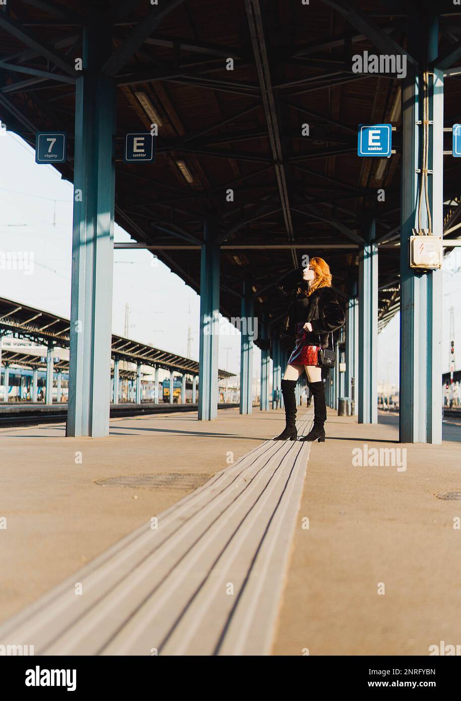 red-haired woman in train station waiting the train Stock Photo
