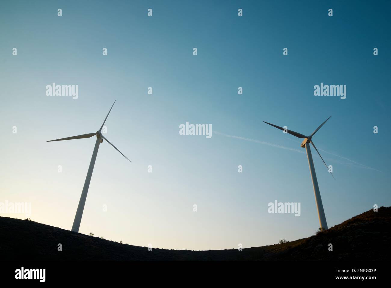 Silhouettes of wind turbines on a hill at sunrise Stock Photo - Alamy