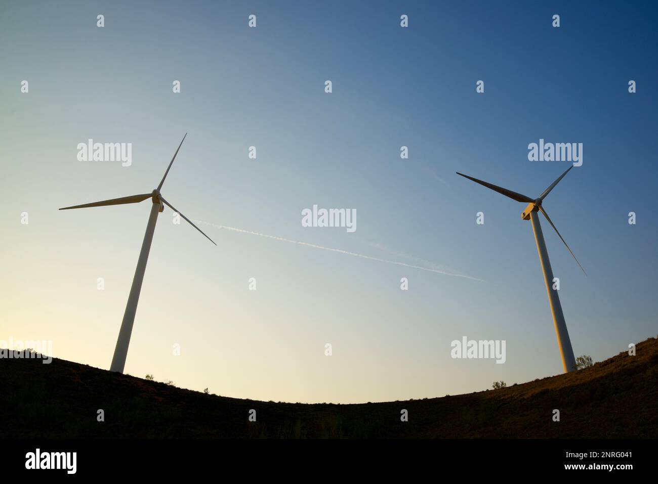 Silhouettes of wind turbines on a hill at sunrise Stock Photo - Alamy