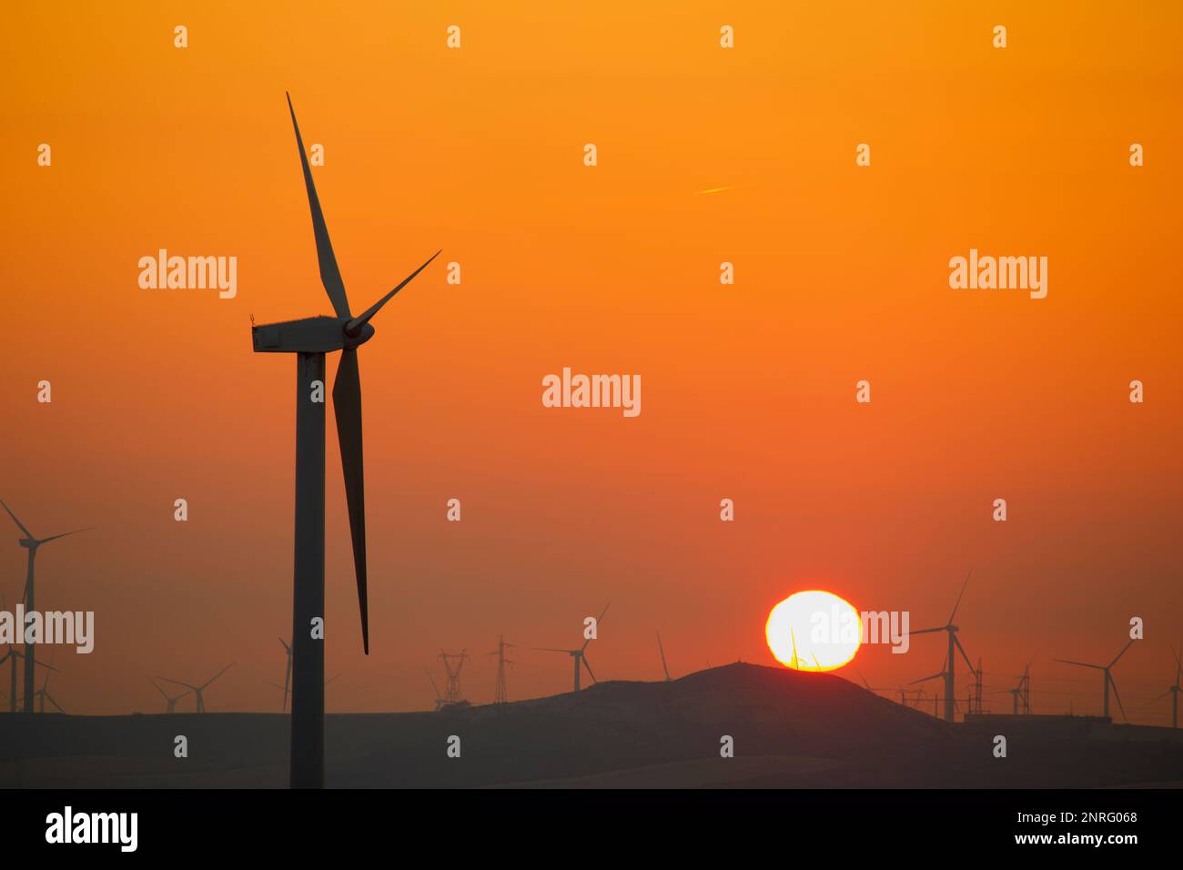 Silhouettes of a group of wind turbines at sunrise over a hill Stock ...