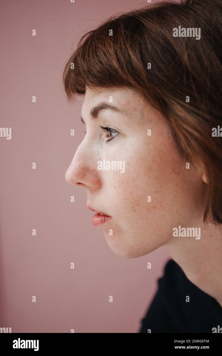 profile of a freckled woman on a pink background Stock Photo