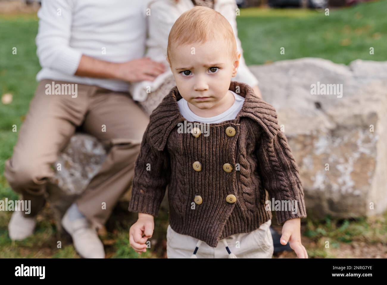 A brown-eyed Caucasian baby boy toddler in a brown knitted sweater Stock Photo