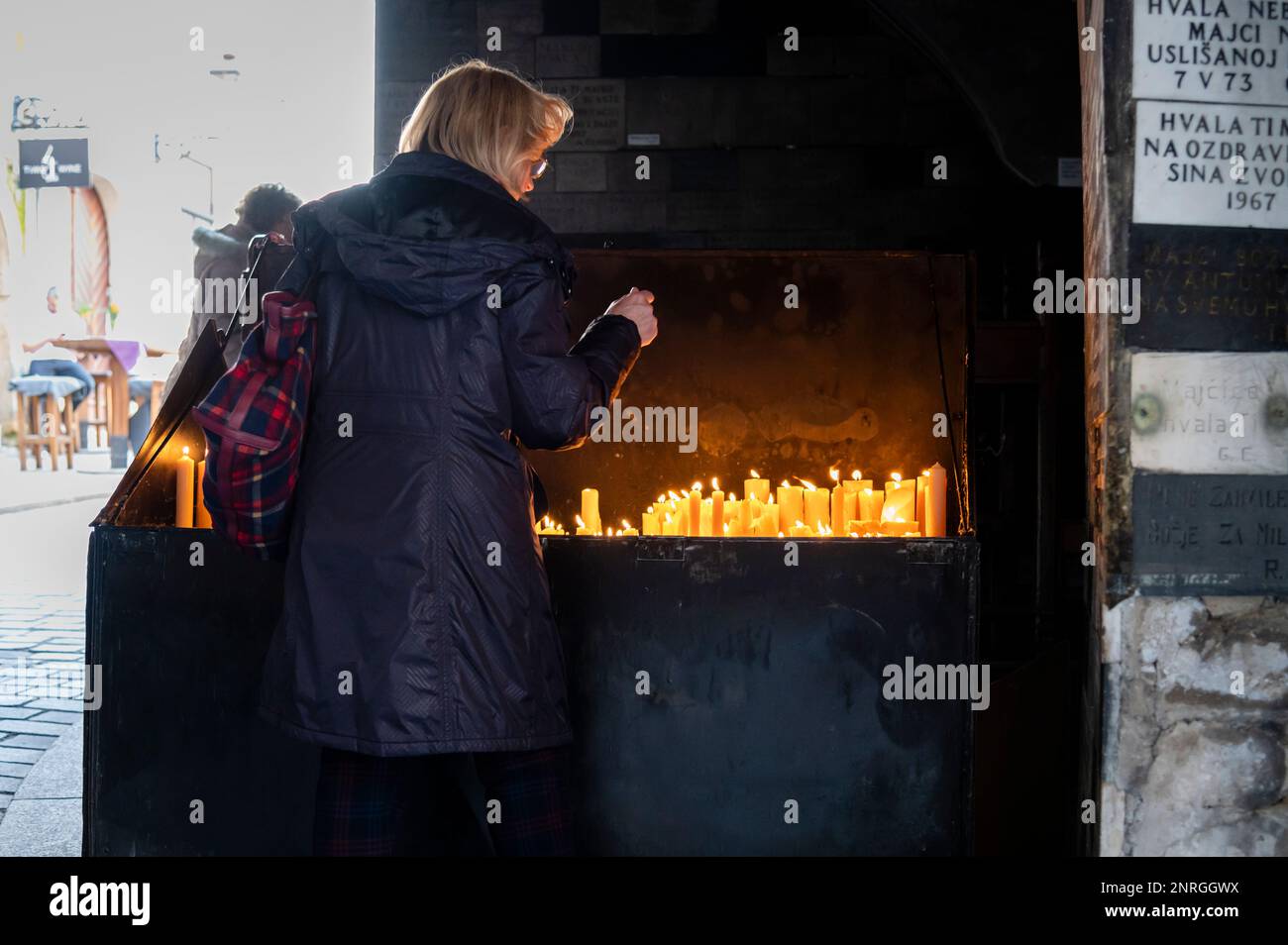 Worshipper lighting a candle Under Stone Gate, Zagreb, Croatia Stock