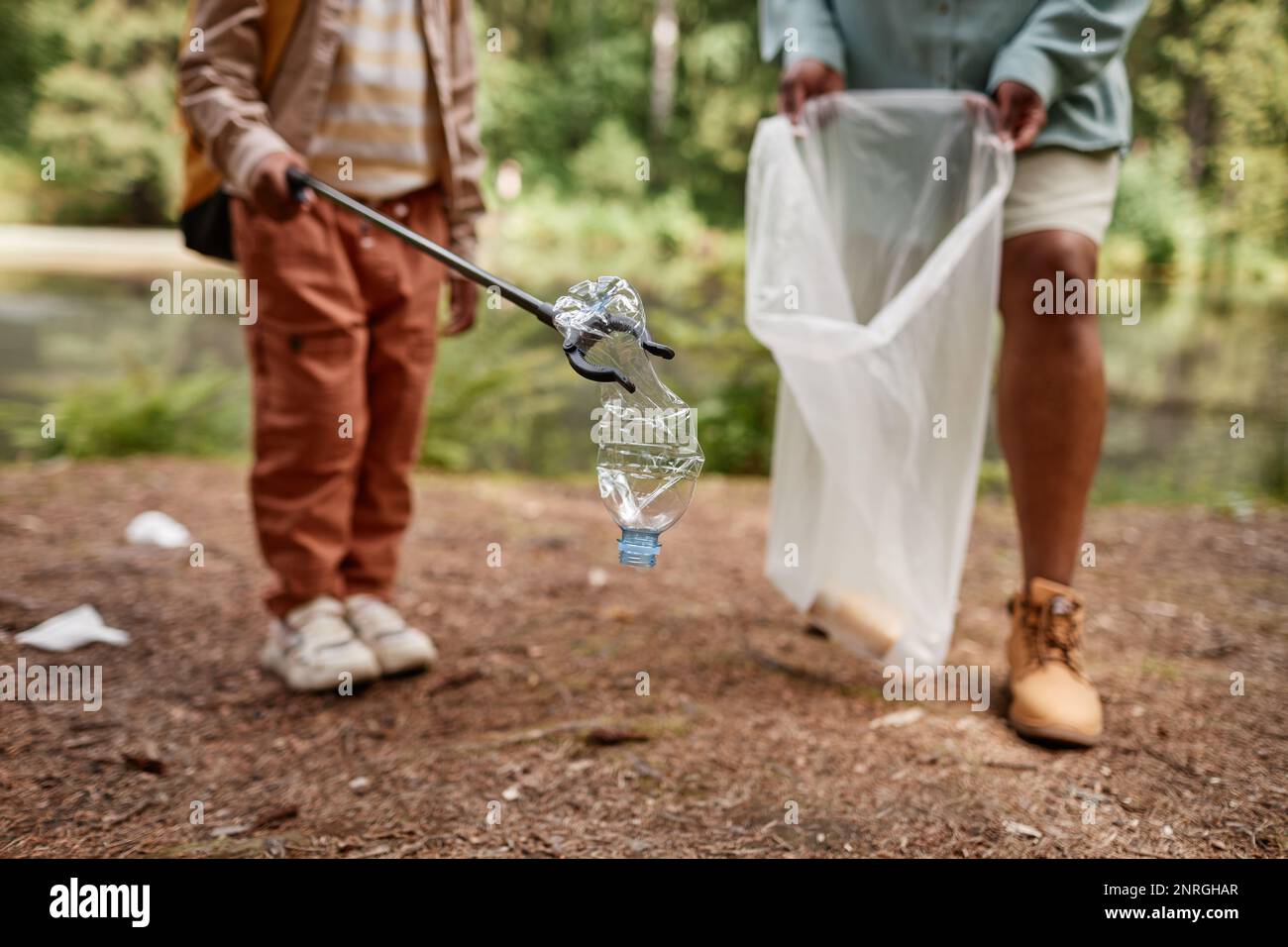 Close up of little girl picking up plastic bottle outdoors helping clean nature, copy space Stock Photo