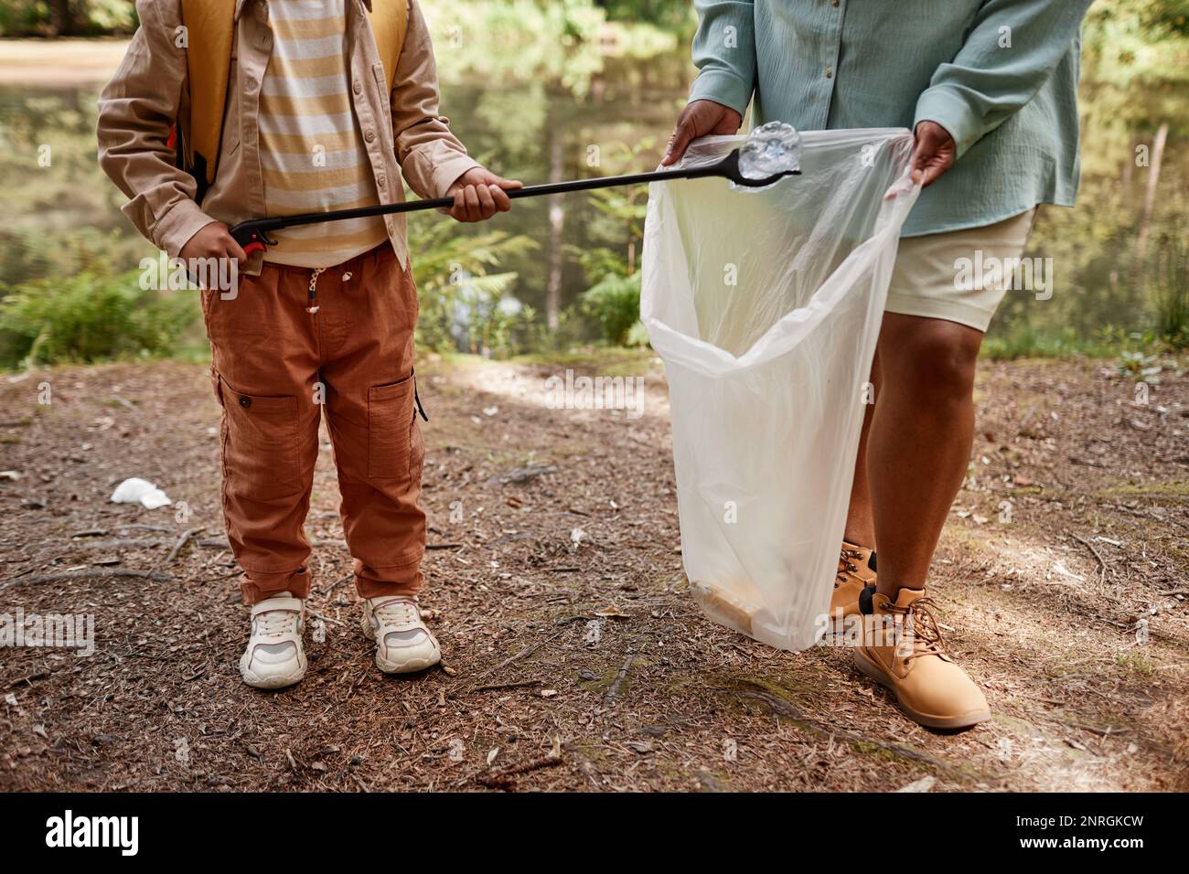 Cropped portrait of child helping clean nature and picking up plastic bottles outdoors Stock Photo