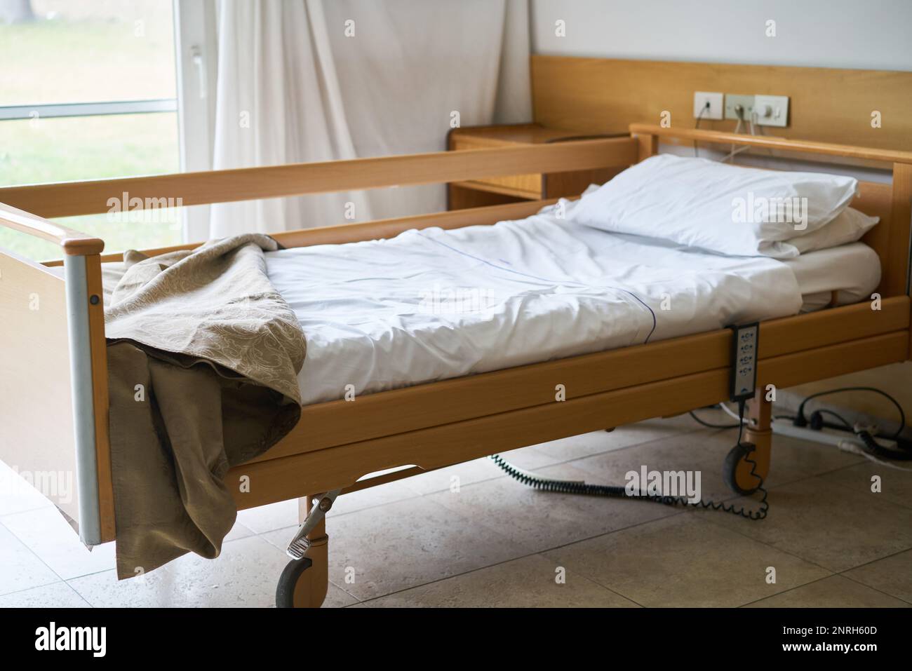 Interior of nursing home with blanket and pillow on empty bed Stock