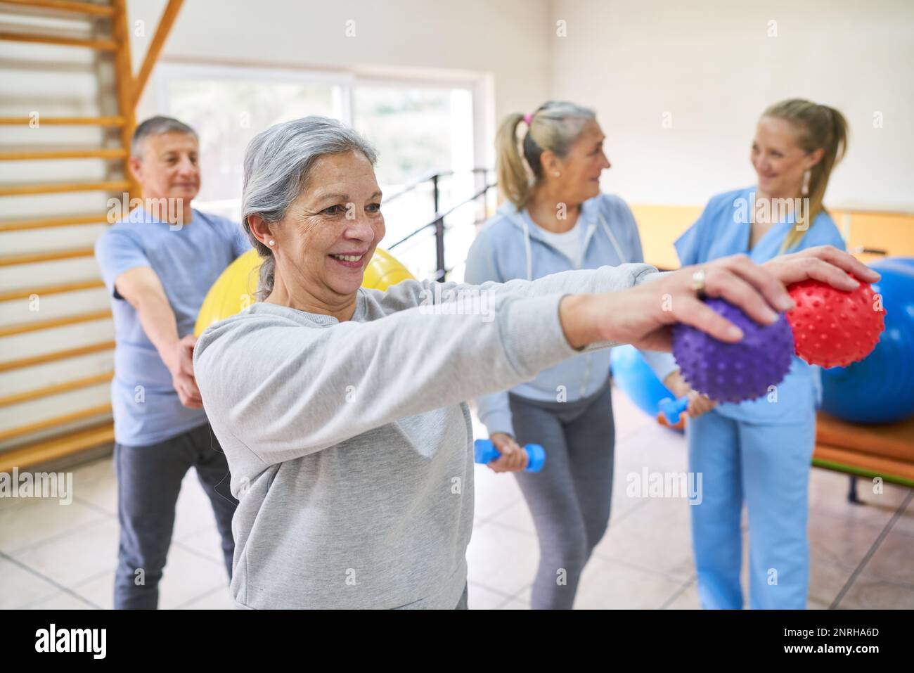 Smiling senior woman exercising with massage balls during exercise class in rehab center Stock Photo