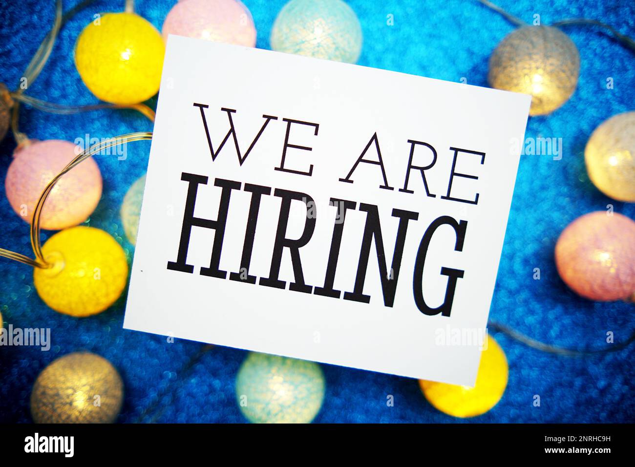 We Are Hiring text on paper card with LED cotton balls decoration on