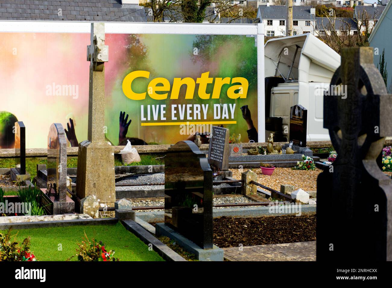 Ardara, County Donegal, Ireland. 27th February 2023. A supermarket delivery truck with Centra advertising creates an ironic juxtaposition by a graveyard in the town. Credit: Richard Wayman/Alamy Live News Stock Photo