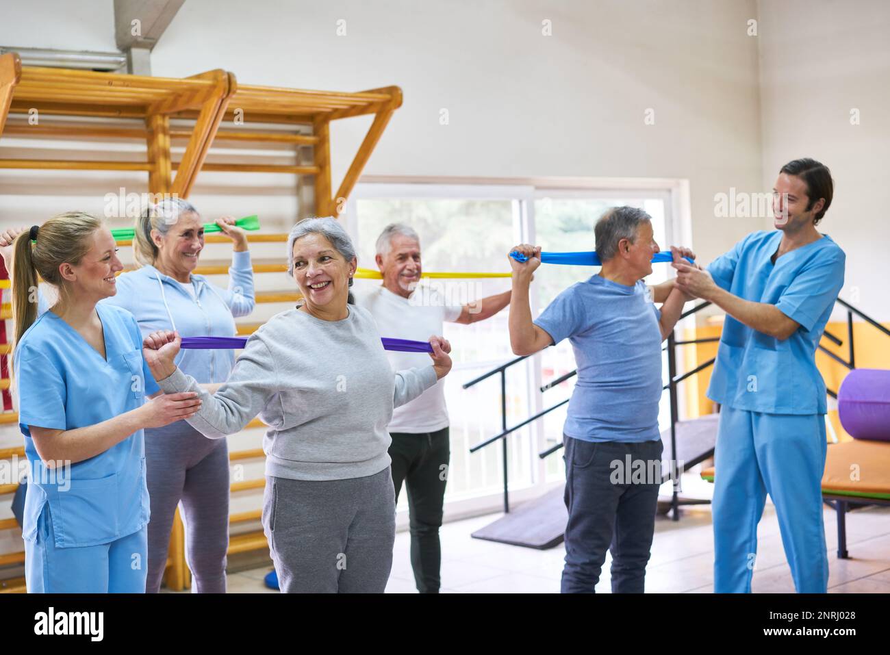 Happy elderly people doing workout with stretch band in fitness class Stock Photo