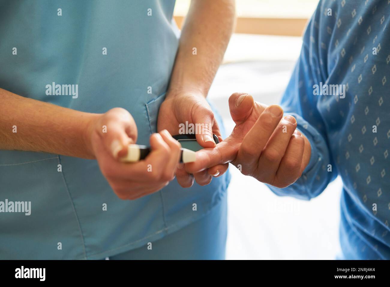 Closeup of nurse checking blood sugar on finger of diabetic senior patient at nursing home Stock