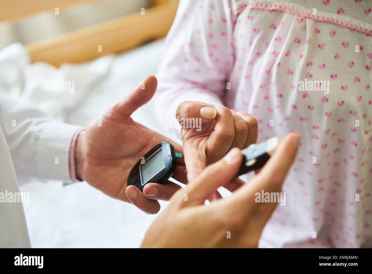 Closeup of male nurse checking blood sugar on finger of diabetic elderly patient in nursing home