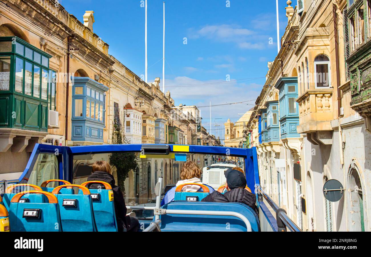 Driving around Malta with hop on hop off sightseeing bus. Beautiful old town in Malta with traditional colorful wooden Maltese balcony The Gallarija. Stock Photo