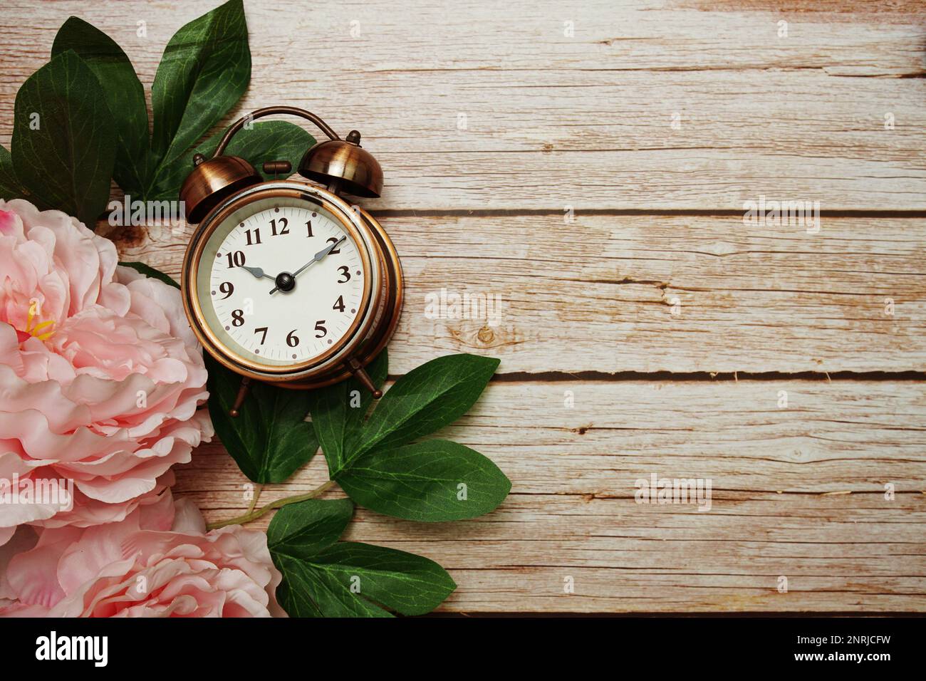 Alarm clock with pink peony flowers border frame on wooden background ...