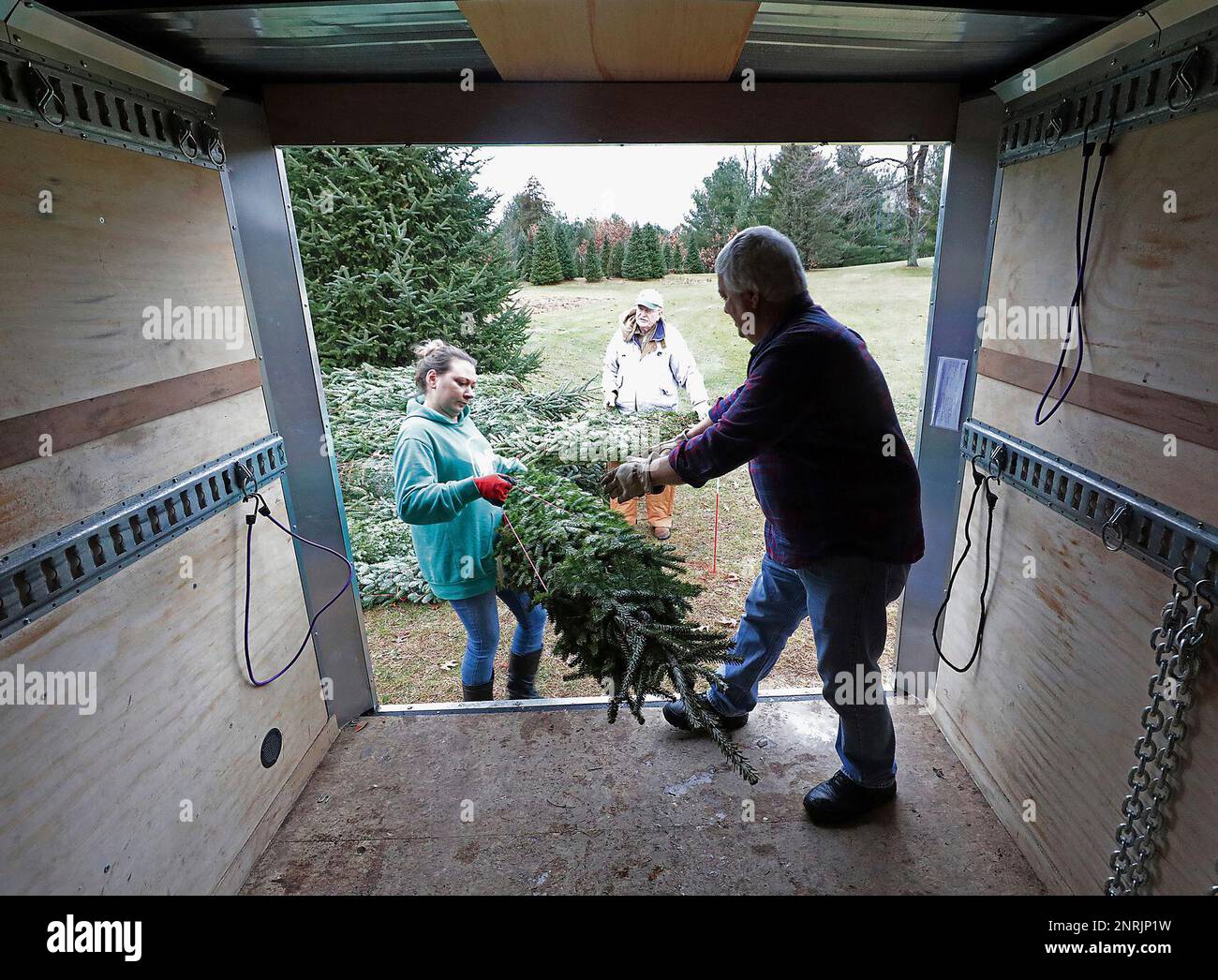 Charlie Fuchs and Megan Martens load Christmas trees into a trailer at