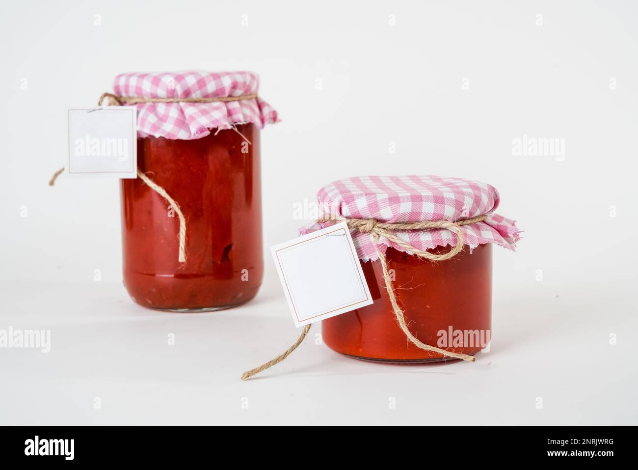 Two canned homemade tomato paste jars with empty labels isolated on