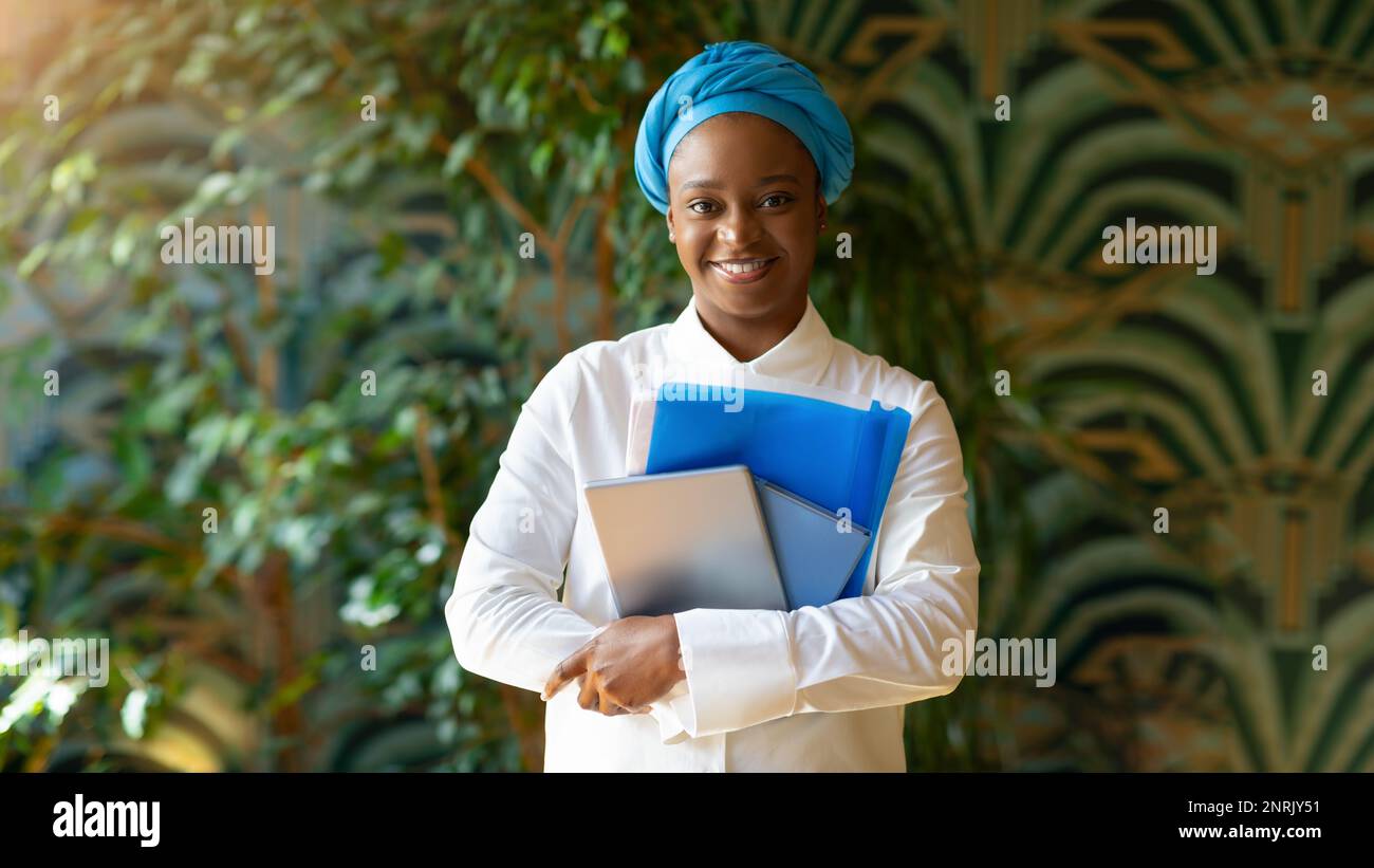 Pretty black lady posing at cafe, holding pad, notebook Stock Photo
