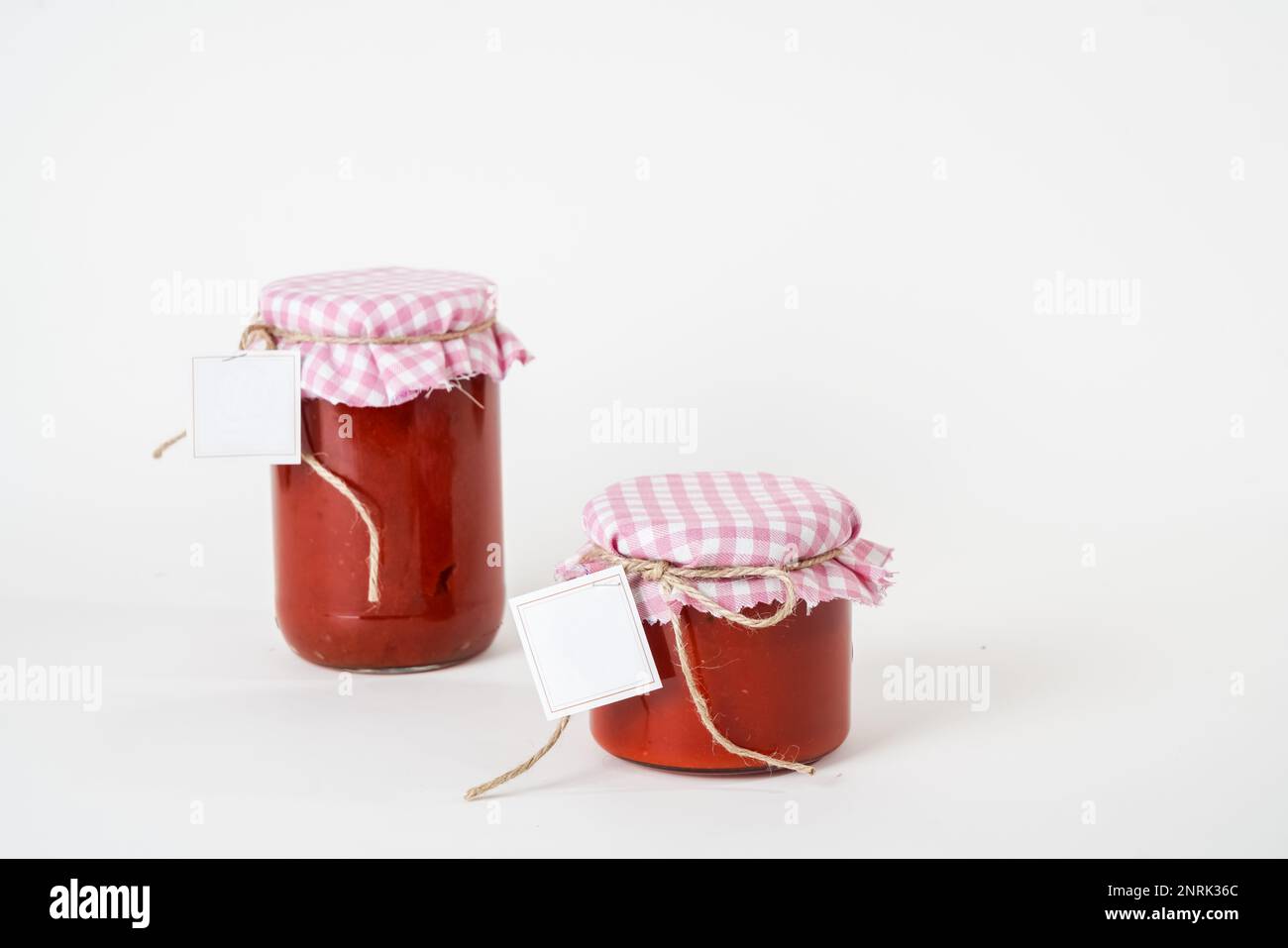 Two canned homemade tomato paste jars with empty labels isolated on