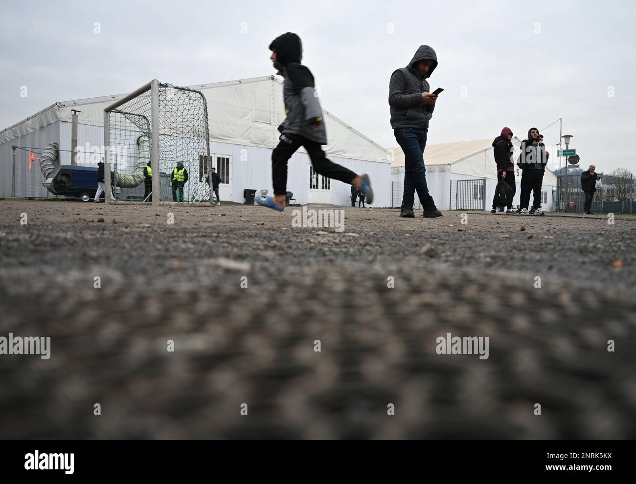 Bensheim, Germany. 10th Feb, 2023. Refugees linger on the grounds of the refugee shelter in front of the tents. Cities and communities can hardly accommodate the number of refugees. The Bergstrasse district is not alone in calling for more support from the federal and state governments. Credit: Arne Dedert/dpa/Alamy Live News Stock Photo