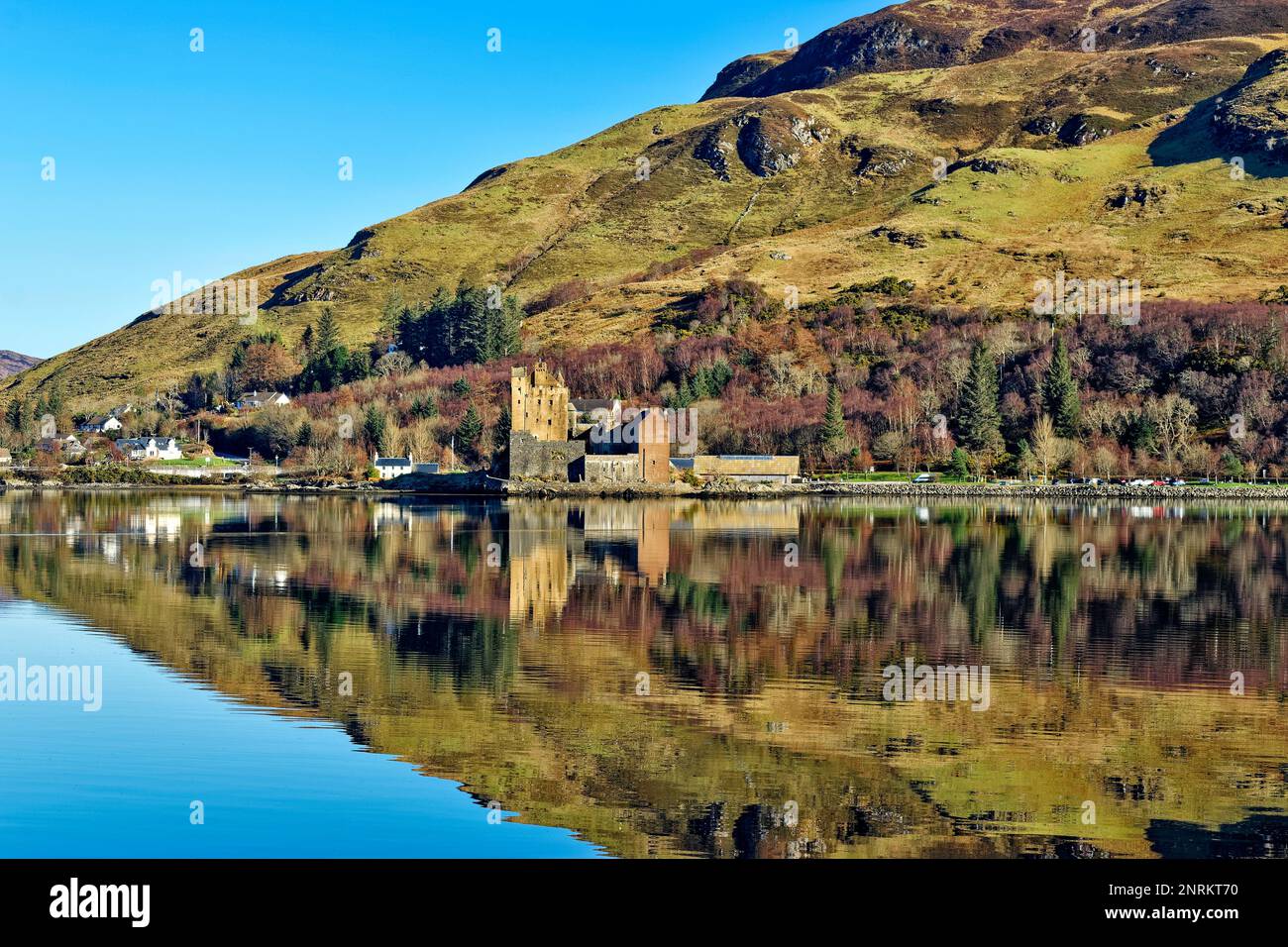 Eilean Donan Castle Loch Duich Scotland colours of the castle hill and birch trees reflected in the sea loch Stock Photo
