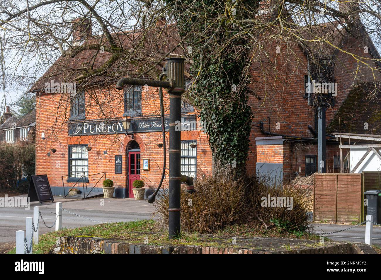 The Purefoy Arms pub in Preston Candover village, Hampshire, England, UK, with the historic village pump Stock Photo