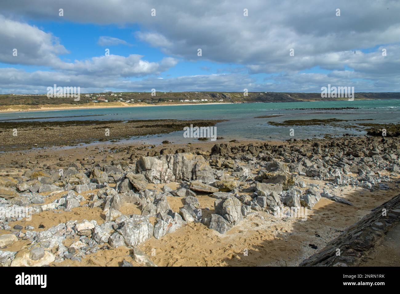 Looking over the rocks of Port Eynon Beach towards Horton Beach and the Cliffs on the Gower Peninsula Stock Photo