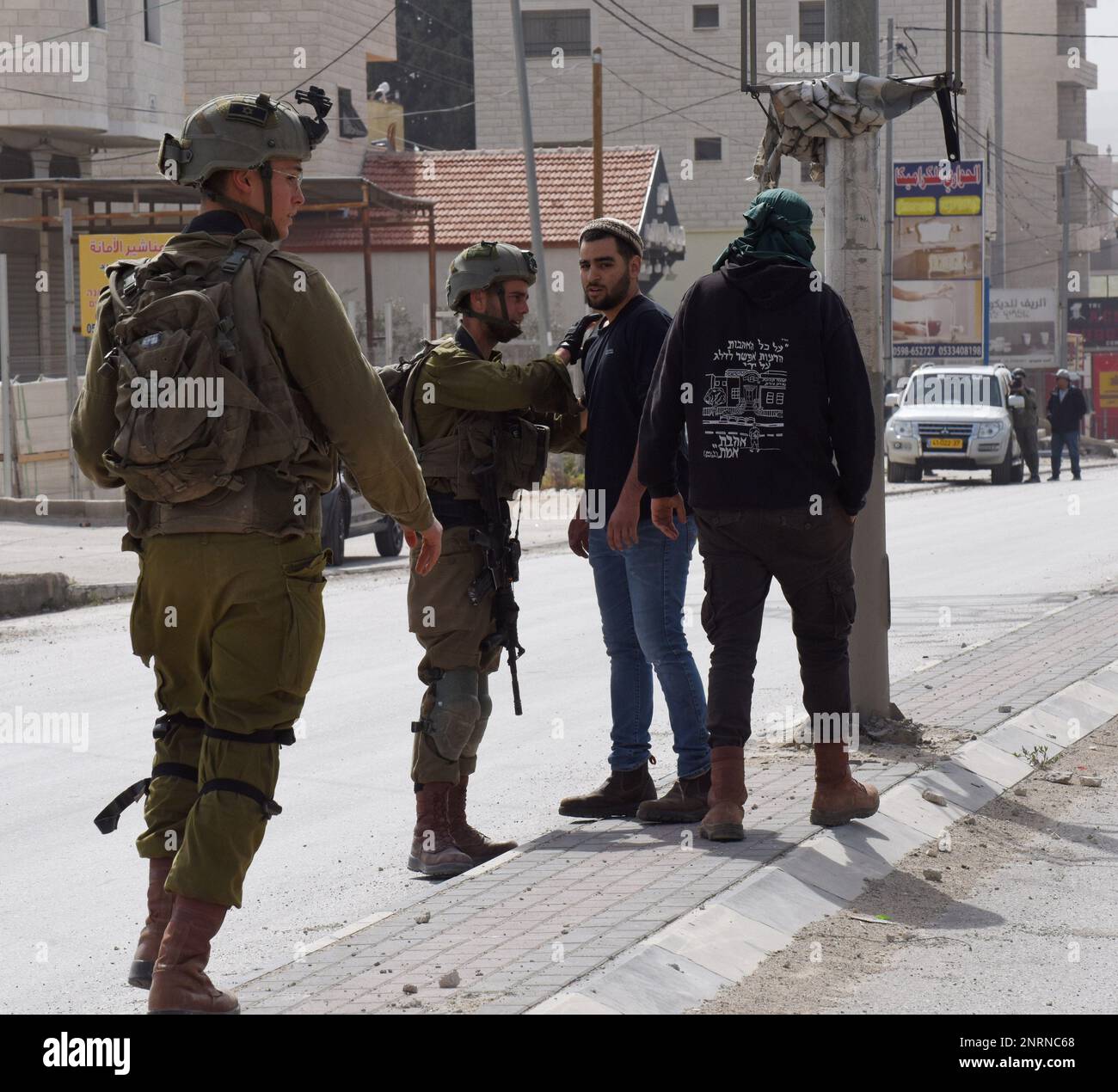 Hawara, Gaza. 27th Feb, 2023. Israeli soldiers protect A Jewish settler in the Palestinian town of Hawara, the morning after settlers burned cars and houses in revenge for two Israeli brothers killed yesterday by a Palestinian gunman in the West Bank, on Monday, February 27, 2023. Photo by Debbie Hill/ Credit: UPI/Alamy Live News Stock Photo